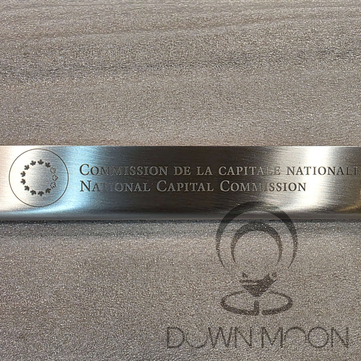 Metallic bar with engraved text and logo on a gray background