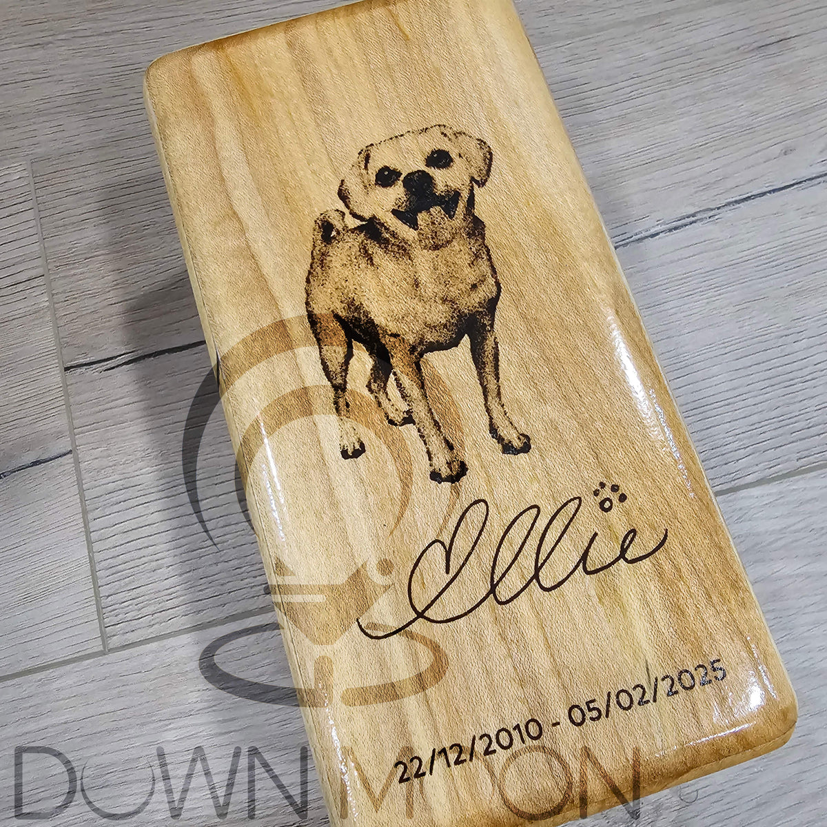 Wooden plaque with a dog illustration and engraved text on a wooden surface